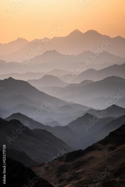 Fototapeta Layered mountain ranges creating misty silhouettes at sunset with orange sky and dramatic depth perspective in shades of grey. Generative AI