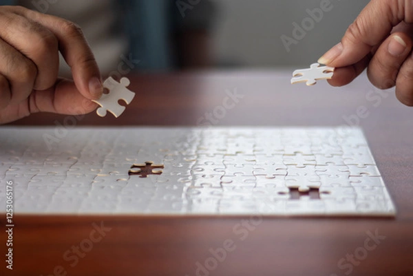 Obraz Two people working together to put together a jigsaw puzzle.