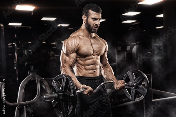 Fototapeta Handsome man with big muscles, posing at the camera in the gym