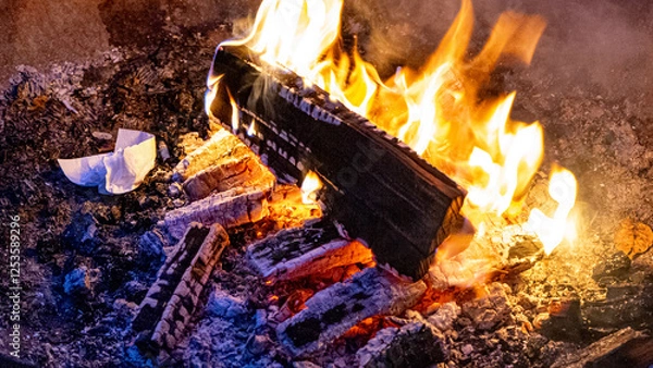 Fototapeta warm camp fire - close up with blue glowing wood and brightly glowing flame and tissue on fire