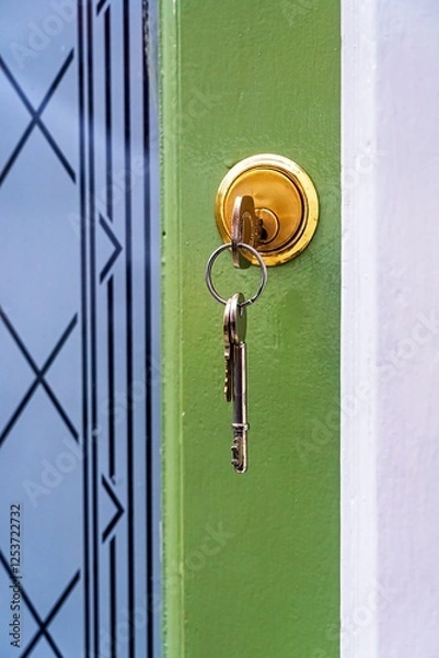 Fototapeta key in the front door of a house with others hanging from key-ring.