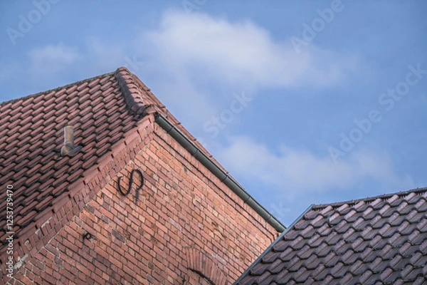 Obraz Historisches Backsteingebäude mit Walmdach Giebelseite mit Maueranker vor blauem Himmel mit Wolken in Pliezhausen