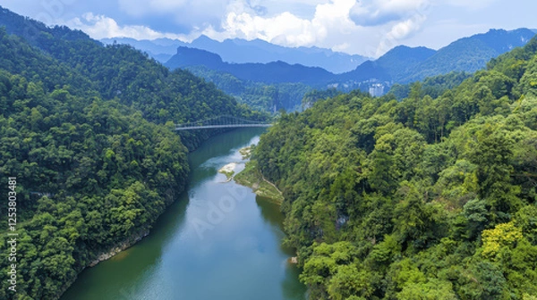 Fototapeta Aerial view of lush green valley with winding river and mountains