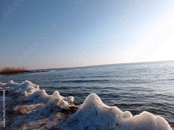 Fototapeta Serene Winter Seascape with Icy Shoreline and Calm Blue Waters, Capturing the Tranquility of a Frozen Beach at Sunset