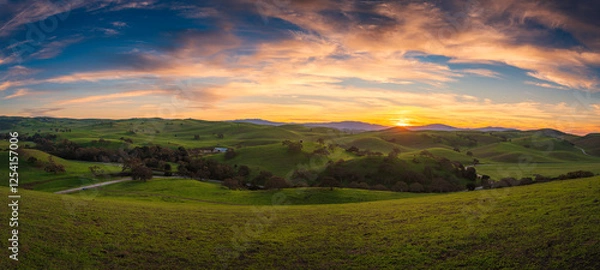 Obraz Sunset over the Mountain Landscape with Green Meadows and Cloudy Skies