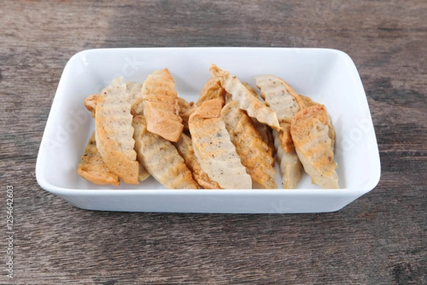 Obraz Fried pork sausage in a white ceramic plate on a wooden table.