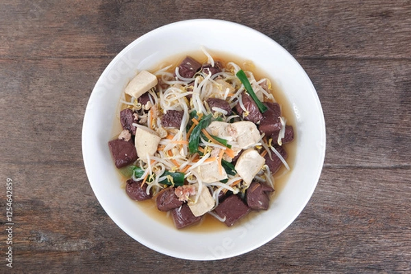 Obraz Stir-fried bean sprouts with minced pork and pork blood cubes in a white ceramic dish on a wooden table.