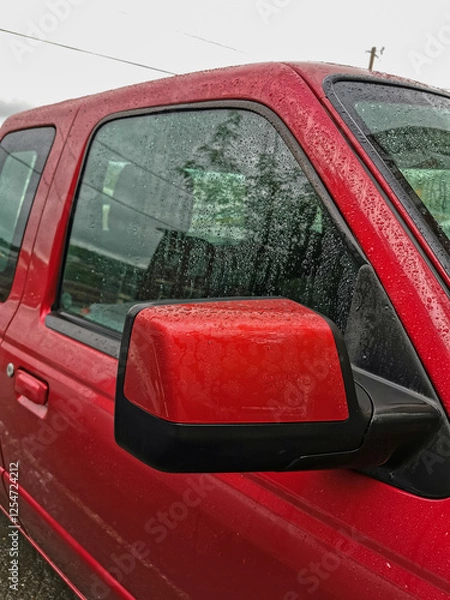 Fototapeta Close-Up of a Red Pickup Truck's Side Mirror and Window with Raindrops, Capturing a Rainy Day Automotive Scene