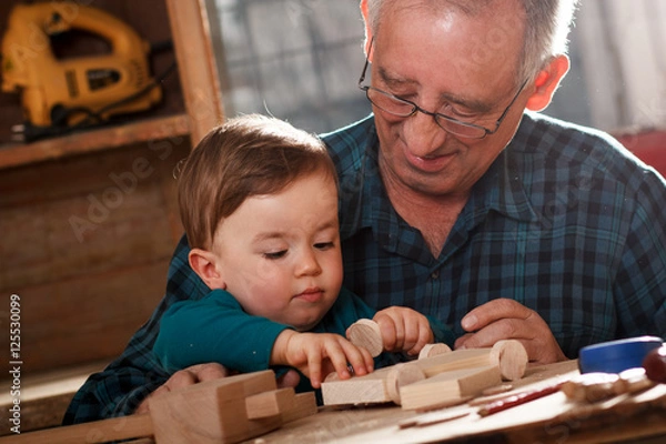 Obraz Senior carpenter and his grandson having fun in the workshop