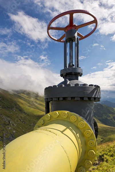 Obraz Yellow gas pipe line valves with mountains background and blue sky with clouds