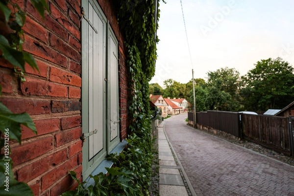 Fototapeta Beautiful small countryside city view with red brick house window on the left side.