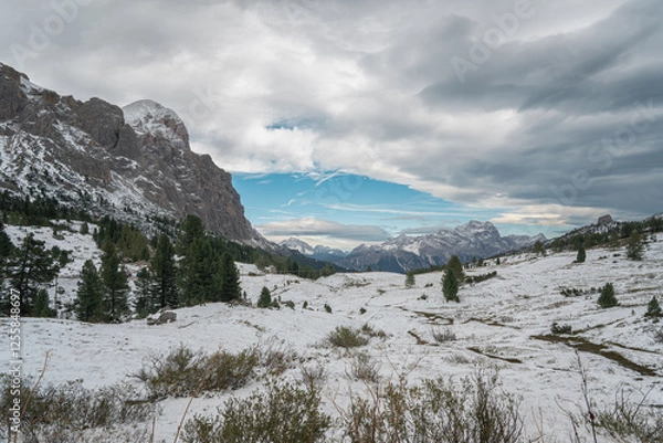Fototapeta Snow-covered alpine meadows and towering mountains under a dynamic sky. A perfect scene showcasing the raw beauty of winter in the Dolomites.