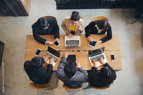 Fototapeta Group of business people plan budget and work via laptop, tablet, and smartphone during brainstorming meeting. Top view of Collaborate with Professional businesswoman and businessman at office