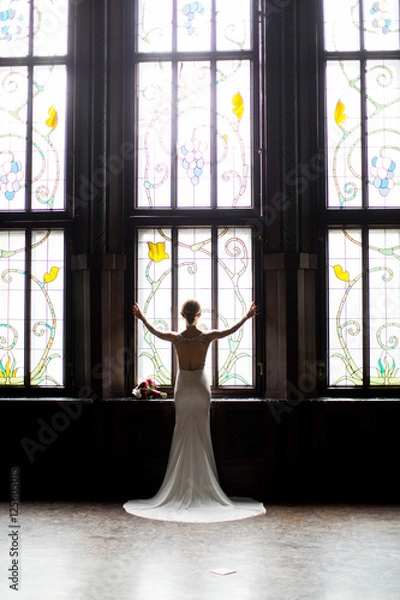 Fototapeta beautiful young girl opened the curtains and looks out the window. bride waiting for groom