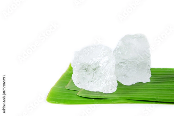 Fototapeta Pieces of white alum sit on a banana leaf, set against a white background. This simple yet meaningful display represents the use of natural minerals in purification, skincare, and household remedies.