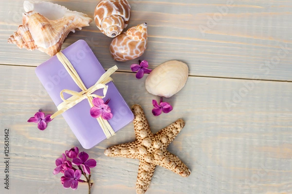 Fototapeta Organic spa soaps with lilac flowers on white wood table. Empty space for text.