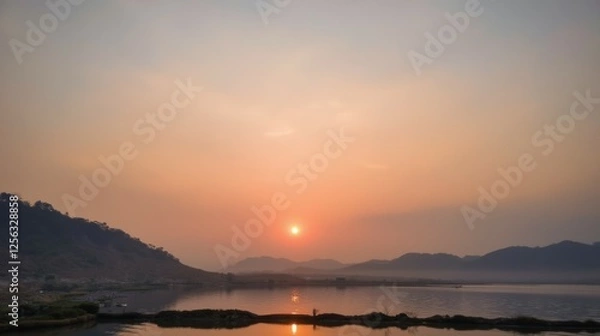 Fototapeta Serene Sunset Over Calm Waters with Hills in the Background