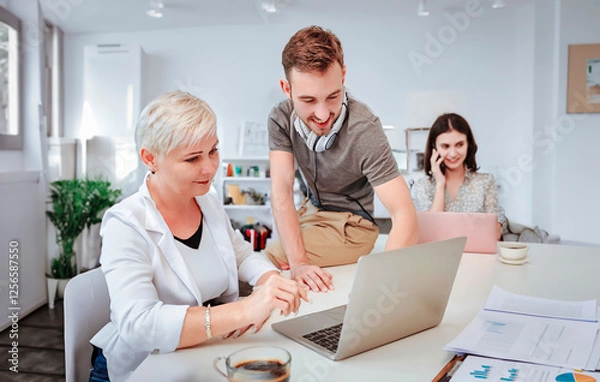 Fototapeta Businesspeople using laptops and team communication while collaborating in an office