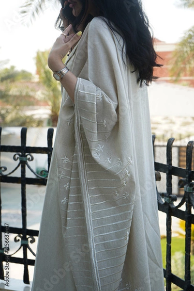 Fototapeta A gracefully designed beige abaya featuring intricate embroidery, reflecting timeless Saudi elegance. The soft fabric, delicate details, and neutral tones create a sophisticated and modern aesthetic.