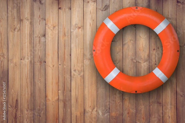 Fototapeta Boja ratunkowa zawieszona na drewnianej ścianie w celu udzielenia pomocy w nagłych wypadkach, gdy ludzie tonący w wodzie prawie umieszczają basen i plażę