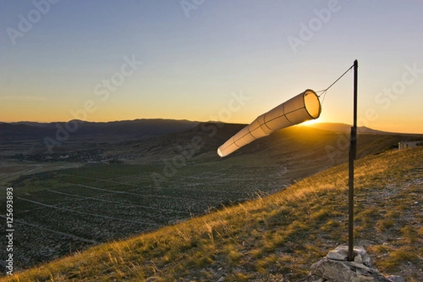 Obraz windsock at sunset in mountains against sun