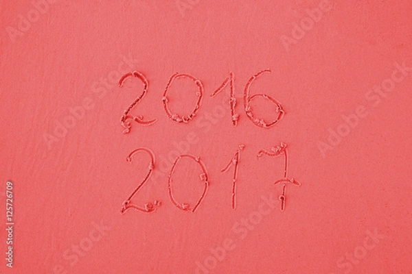 Fototapeta 2016 and 2017 written on sand at the beach in red colors. Greeting card