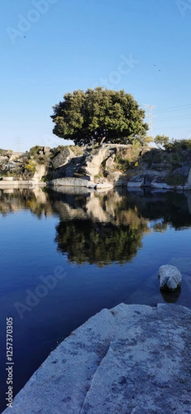 Obraz Calm lakeside view on a clear day with gentle ripples reflecting surrounding rocks and grassy shore