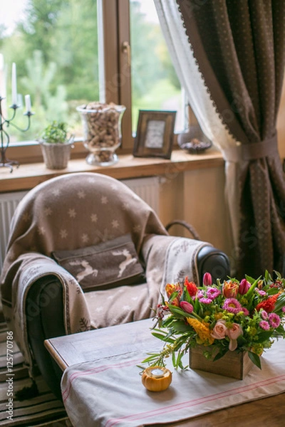Fototapeta Daybed with cushions in rustic home. on the table bouquet of flowers and a candlestick pumpkin