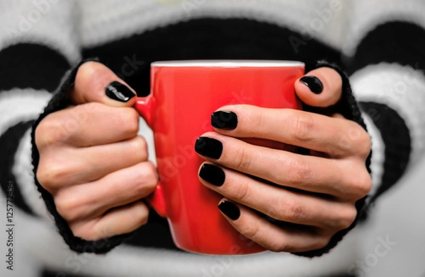 Fototapeta Hot drink in a red cup in his hands