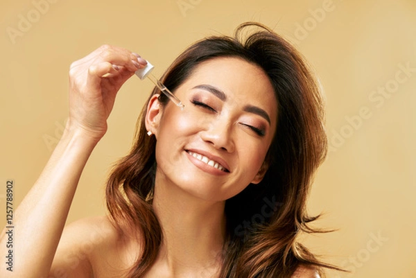 Fototapeta Happy smiling woman applying facial serum using pipette dropper. Moisturising and nourishing.