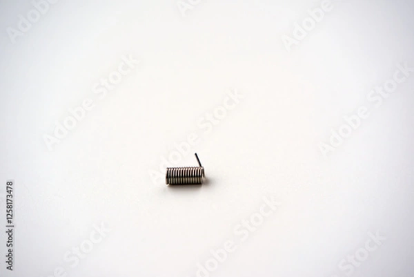 Fototapeta High angle view of small metal coil spring against white background. Photo taken February 11th, 2025, Zurich, Switzerland.