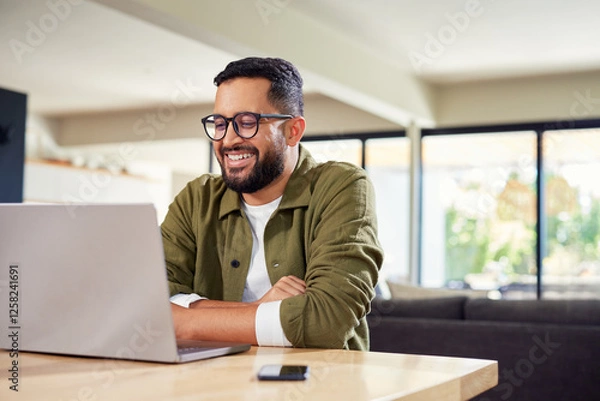Fototapeta Happy hispanic man working on laptop at home
