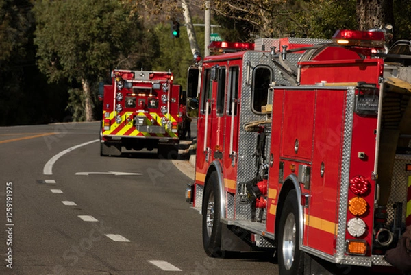 Fototapeta Red fire engines respond to the scene of an emergency.