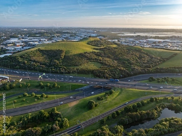 Fototapeta High-angle view of a highway intersecting with a grassy area and a body of water. Traffic flows smoothly through the urban landscape. MT WELLINGTON, AUCKLAND, NZ