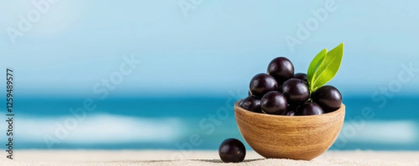 Fototapeta A bowl of acai sits on a sandy surface with a serene ocean backdrop, showcasing freshness and natural beauty.