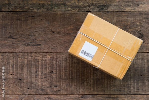 Fototapeta cardboard box taped up on wooden table with copy space.