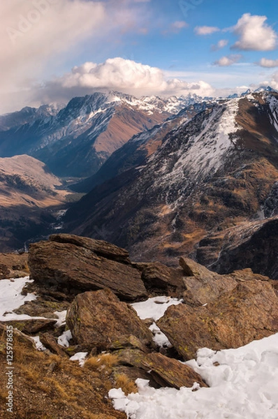 Obraz Ski resort Cheget. View on the Main Caucasian ridge and Baksan gorge. Textured stones with lichen covered with snow in the foreground. Caucasus