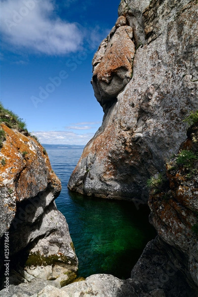 Obraz Clear emerald water in a small bay surrounded by strange shape cliffs. On the rocks growing moss and lichen. Summer, Lake Baikal, Olkhon Island