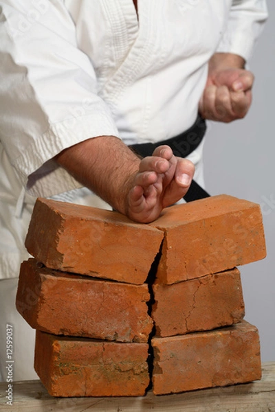 Fototapeta karate man breaking three bricks on white background