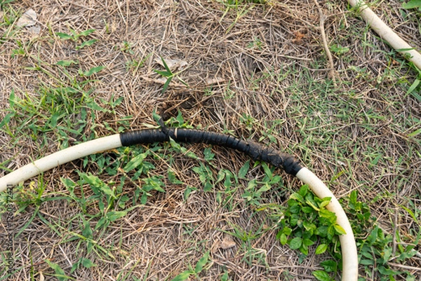 Fototapeta An old hose that leaks and is fixed by wrapping it with a rubber band.