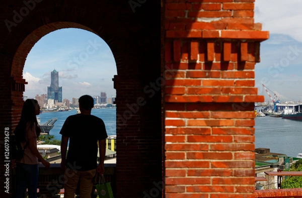 Obraz Tourists stand at the arch corridor of the historic architecture of Former British Consulate in Takao, Taiwan & enjoy a panoramic view of Kaohsiung Harbor with the landmark 85 Sky Tower in background