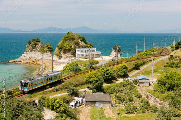 Obraz A local train travels on JR Yosan Railway  along the beautiful coastline and Komogahana (a small headland) extends into the blue water of Seto Inland Sea near Oura, in Matsuyama, Ehime, Shikoku, Japan