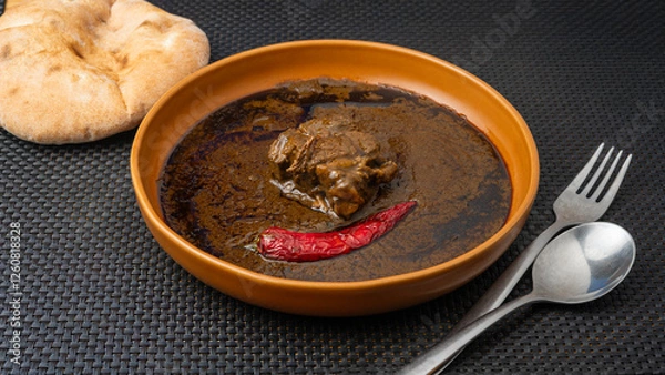 Fototapeta  Traditional Tunisian molokhia is made with jute leaves and beef, with red pepper and flatbread on the table