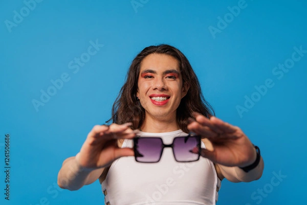 Obraz non-binary stylish person, trans men wearing glasses posing with happy face on blue background with copy space