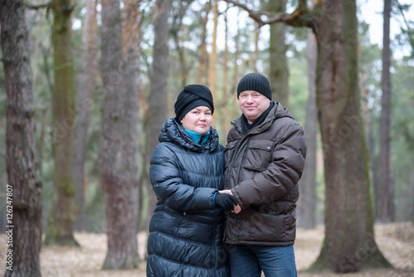Fototapeta Old couple walking in the forest. Having a good time together. Smiling and talking on autumn or spring