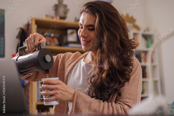 Fototapeta Non-binary person serving coffee at their desk to start the work day