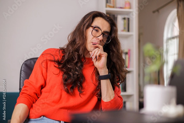 Fototapeta Non-binary person working from home with their laptop with a thoughtful face