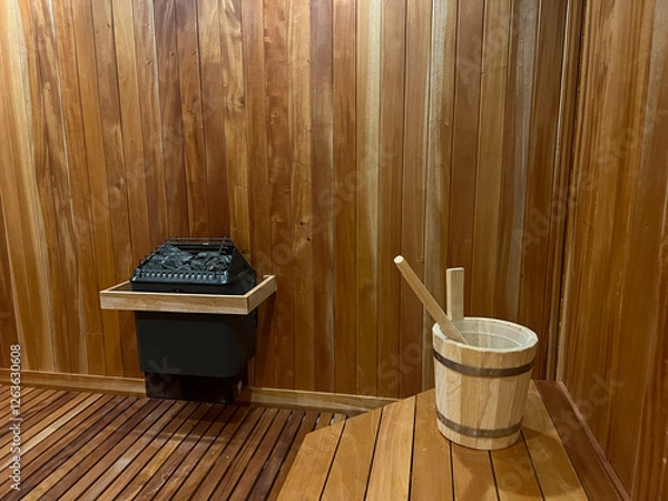 Obraz Inside of an indoor sauna at a spa, showing the water bucket and sauna stones to create humidity in the dry room.