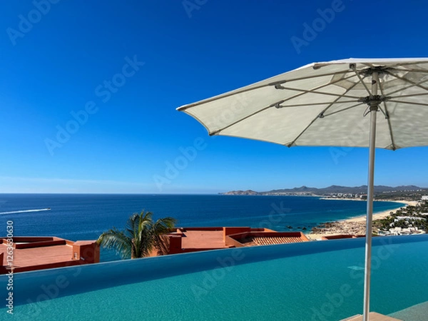 Obraz Infinity poolside view at a Los Cabos resort with a beach umbrella, overlooking the Sea of Cortez.