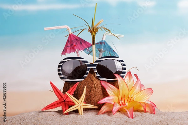 Obraz Coconut, sunglasses, starfish and flower in the sand against sea.